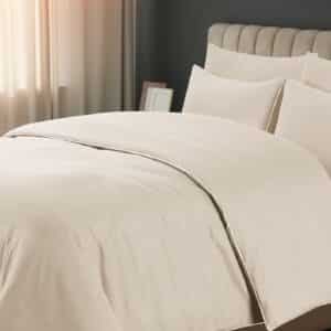 Comfortable bed with soft blanket near window indoors